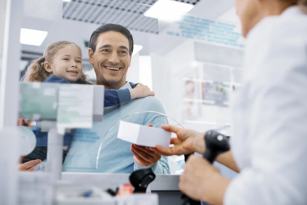 Low angle of female pharmacist transmitting medication and man holding girl