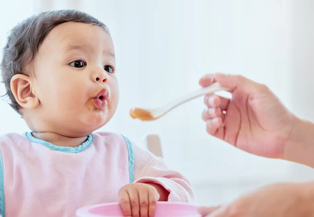 Mother, feeding baby girl with spoon