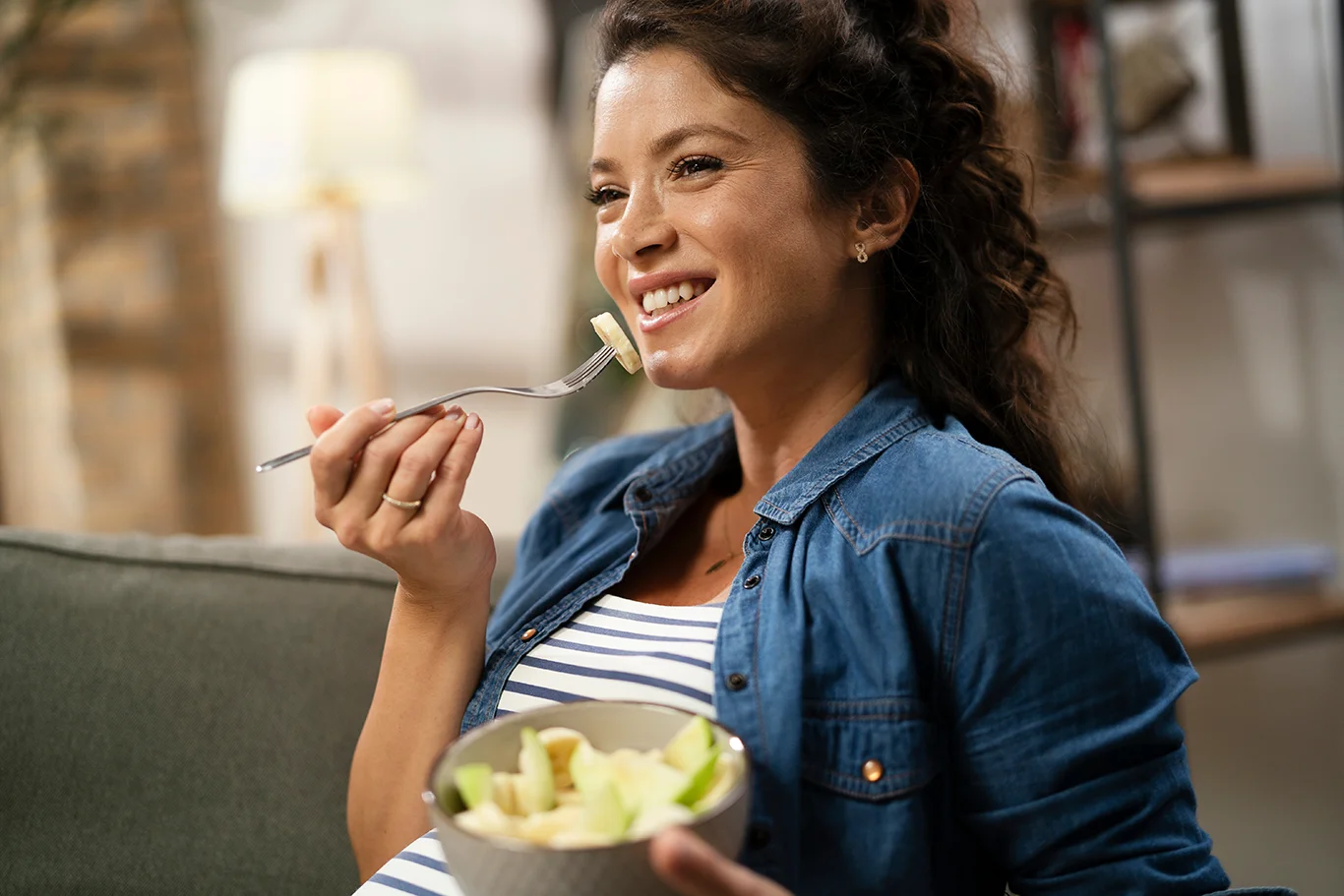 Pregnant woman eating fuit at home.